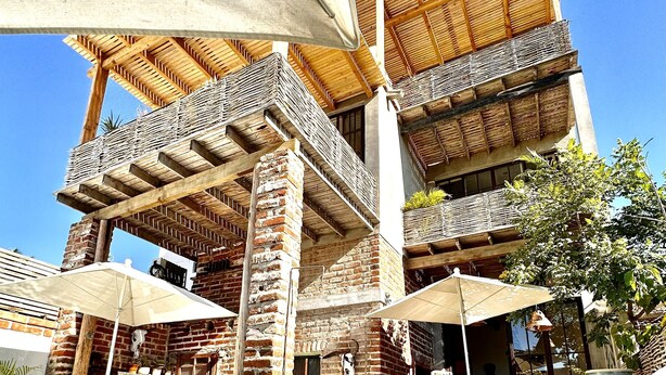 A multi-story building with a pool, outdoor seating, and potted plants. - TS3 Queen in Todos Santos (Todos Santos)