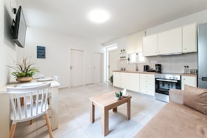 A modern kitchen with white cabinets, a built-in oven, and a dining area with a table and chairs. - Chrisa s Detached Property Near Center Parking (Heraklion)