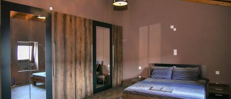 Une chambre avec un lit en bois, un grand miroir et un plafond en bois.