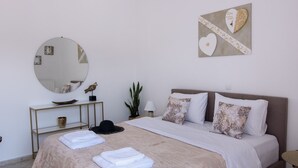 Quarto com cama, mesas de cabeceira, espelho, ventilador de teto e uma obra de arte na parede.