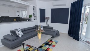 Uma sala de estar moderna com um sofá cinzento, uma mesa de centro e um tapete colorido.