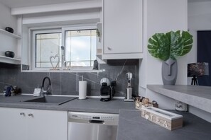 A modern kitchen with a dishwasher, coffee machine, and heart-shaped decorations on the window. - Angel Apartment at Amoudara (Malevizi)