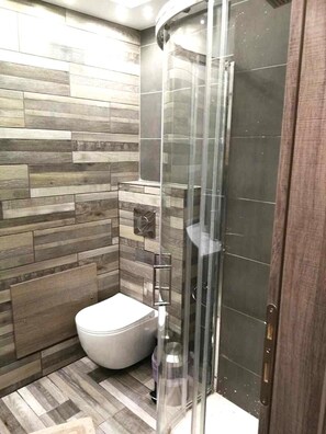 Une salle de bain moderne avec une douche, des toilettes et un plancher en bois.