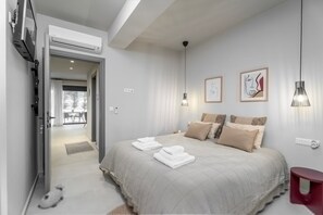 A bedroom with a bed, pillows, a red side table, and artwork on the wall. - Spei Luxury House With Private Pool (Heraklion)