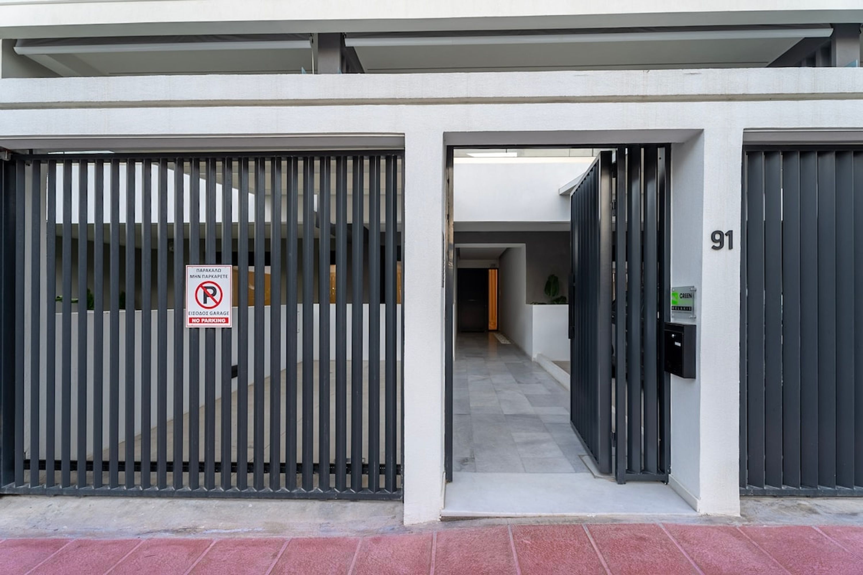 A gated entrance with a 'No Parking' sign, a number '91' on the wall, and a green sign indicating a 'Green Card' area.