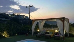 Ein Schwimmbecken mit Sonnensegel und Liegestühlen.
