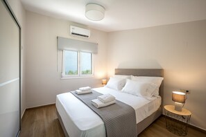 Une chambre à coucher avec un lit, des lampes de chevet, une fenêtre et un appareil de climatisation.