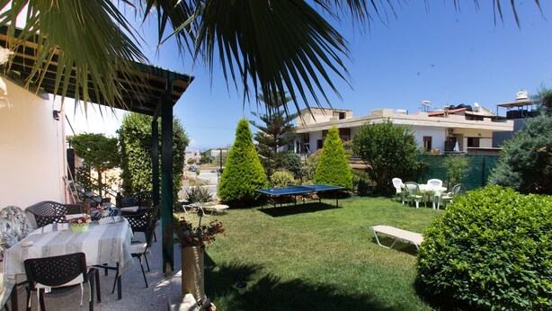 Une terrasse avec des meubles d’extérieur, une table de ping-pong et une pelouse bien entretenue.