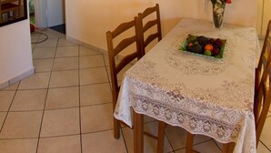 Un coin repas avec une table dressée pour quatre personnes, des chaises, un vase avec des fleurs et des œuvres d’art murales.
