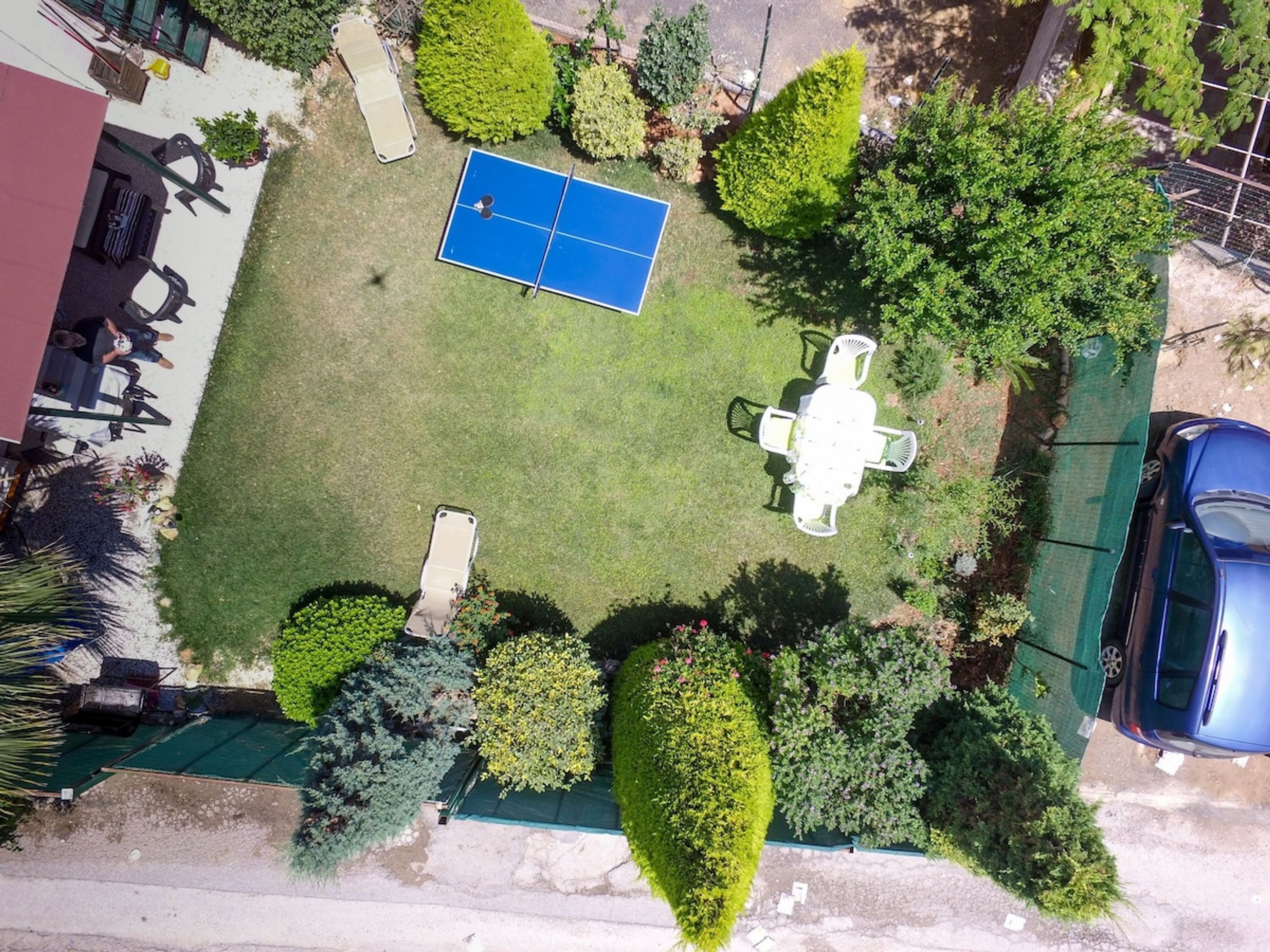 A rooftop garden with a tennis court, seating area, and surrounding greenery.