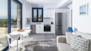 Una cucina moderna con mobili bianchi, una finestra con cornice blu e un frigorifero in acciaio inossidabile.