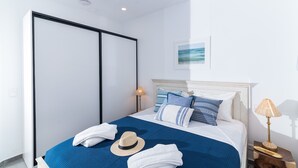 Una camera da letto con un letto, un armadio, un comodino con una lampada e un quadro appeso al muro.