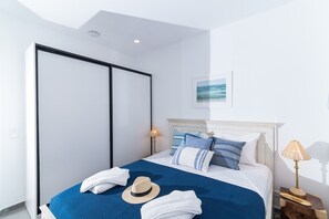 Ein Schlafzimmer mit Bett, Kleiderschrank, Nachttisch mit Lampe und einem gerahmten Bild an der Wand.