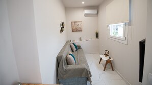Uma sala de estar moderna com um sofá, uma mesa pequena e uma janela.