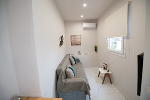 A modern living room with a sofa, a small table, and a window. - Aretousa Apart Heraklion City (Heraklion)