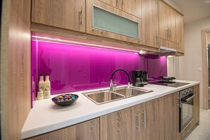 A modern kitchen with wooden cabinets, a stainless steel sink, a black coffee maker, and a microwave. - Aretousa Apart Heraklion City (Heraklion)