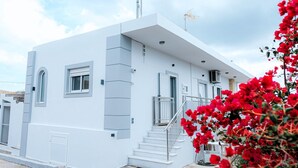 Ein modernes, weißes Gebäude mit Treppe, Fenstern und einem Balkon.