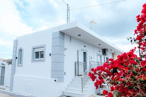 Un bâtiment moderne de couleur blanche, doté d’un escalier, de fenêtres et d’un balcon.