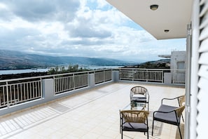 A balcony with a view of a lake and mountains, two wicker chairs, and a table. - Aithra House With Beautiful View (Chania)