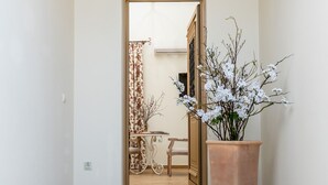 A hallway with a potted plant, a door leading to another room, and a small table with chairs. - Cretan Rhapsody Villa With Private Yard (Faistos)