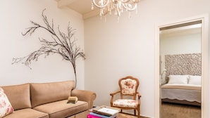 A living room with a sofa, a wooden coffee table with books, a decorative branch, and a chandelier. - Cretan Rhapsody Villa With Private Yard (Faistos)
