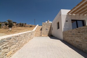 A paved pathway leading to a modern building with stone walls and a clear blue sky. - Kyma Luxury Villa With Private Pool (Faistos)