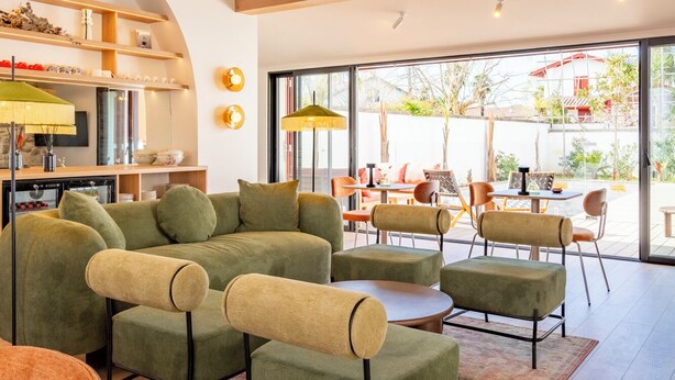 A spacious living area with a large sofa set, a dining table with chairs, and a kitchen area with a built-in oven. - Hôtel Villa Maitia (Ustaritz)