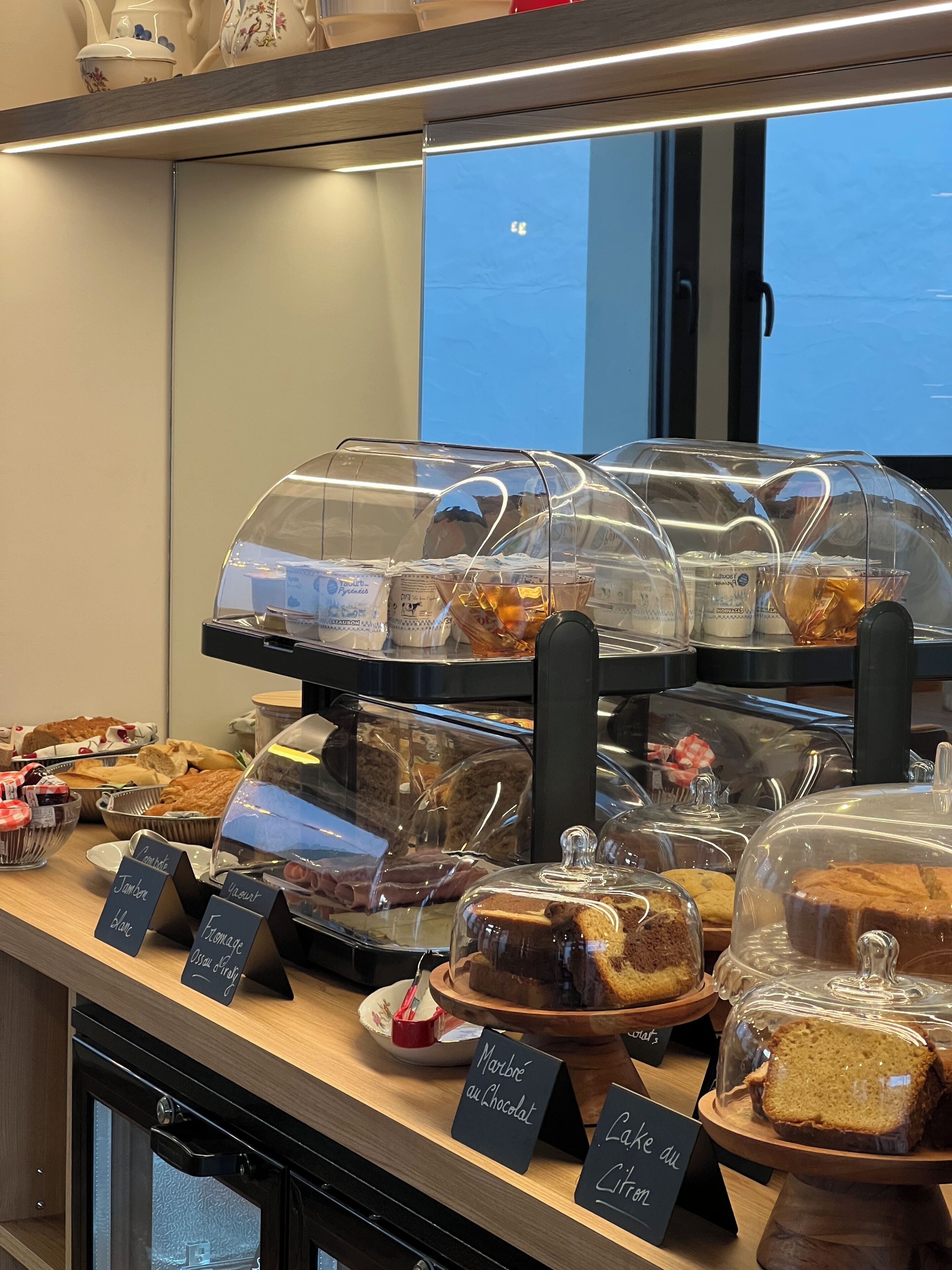 Une vitrine de boulangerie présentant diverses pâtisseries et pains sous des cloches de verre.