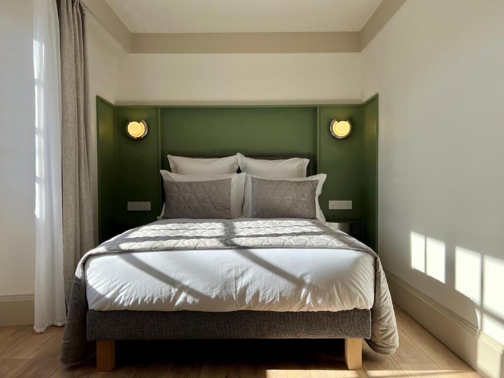 Een slaapkamer met een bed, groene wanden en twee wandlampen.