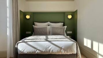 Een slaapkamer met een bed, groene wanden en twee wandlampen.