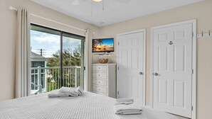 A bedroom with a bed, a television, a wardrobe, and a balcony with a view. - Sunrays Anchor by Duncan Real Estate (Holmes Beach)