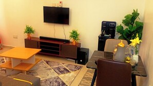 Un salón con televisión, cafetera y dos plantas en macetas.