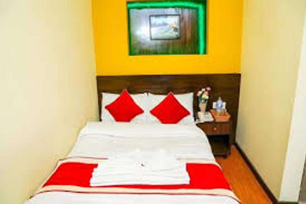 Una habitación de hotel con una cama, una mesita de noche y un marco de fotos en la pared.