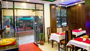 Un restaurant avec des portes vitrées, des tables à l’intérieur et une vue sur la rue.