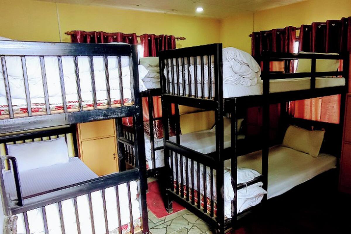 Camas literas en una habitación con paredes amarillas y cortinas rojas.
