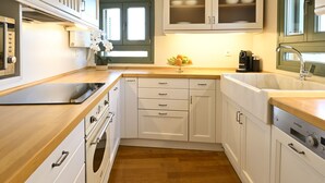 A kitchen with white cabinets, wooden countertops, a built-in oven, and a window. - Ma Maison N°10 Elegant Plaka Villa under Acropolis (Athens)