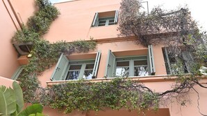 A building with a pink facade, green shutters, and a balcony with climbing plants. - Ma Maison N°10 Elegant Plaka Villa under Acropolis (Athens)