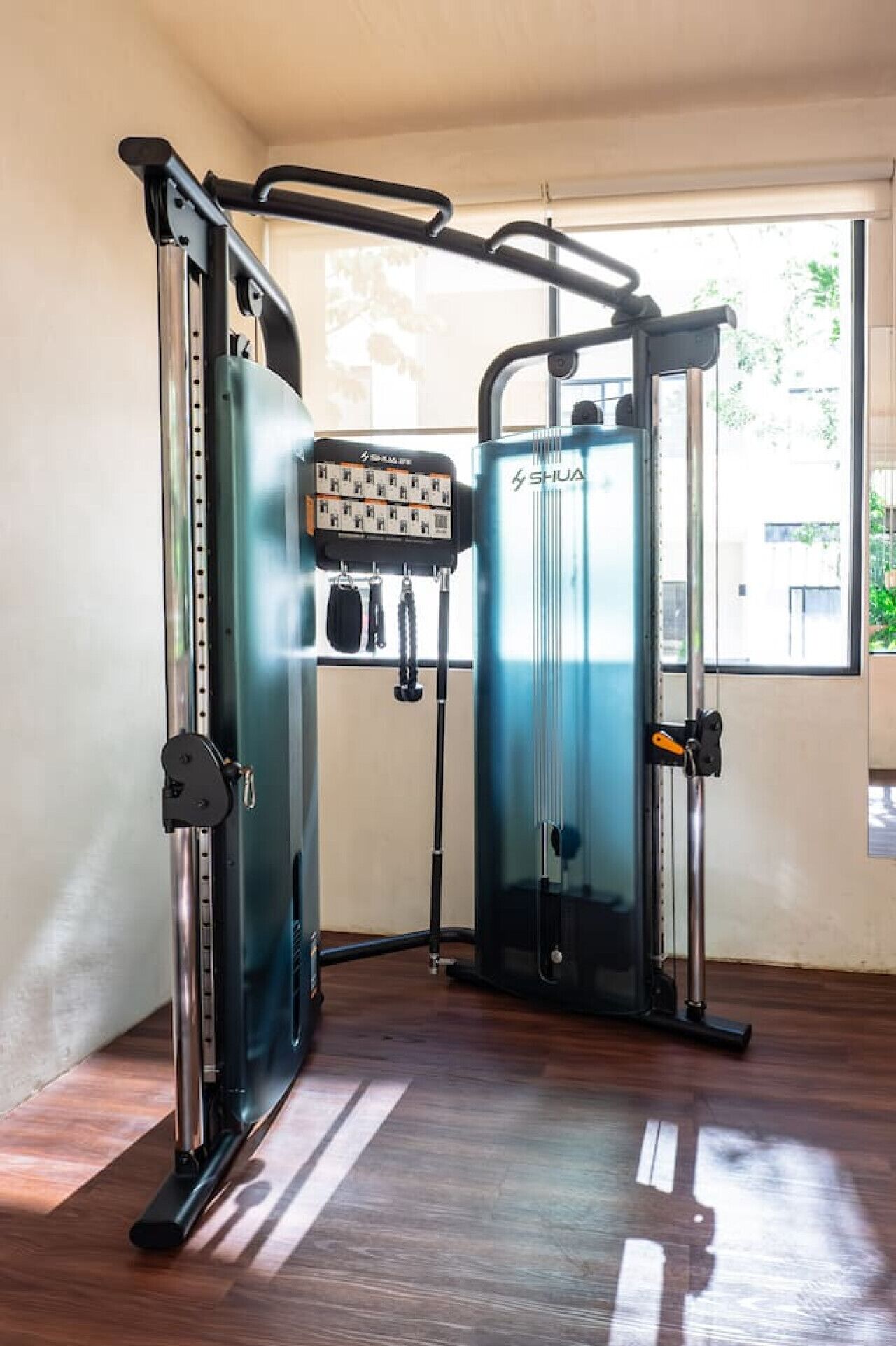 A gym with exercise machines, a power outlet, and a window with a view.