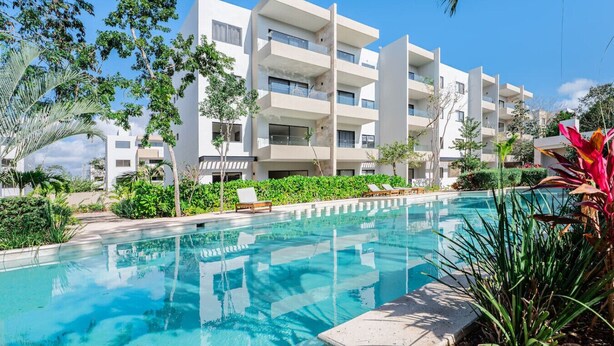 Un hôtel moderne doté d’une piscine, entouré de verdure et de palmiers.