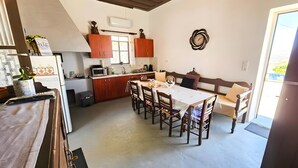 Cuina amb armaris de fusta, una taula de dinar, caires i un microones.