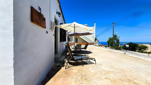 Una casa tradicional amb un pati, mobiliari d'exterior i vista al mar.