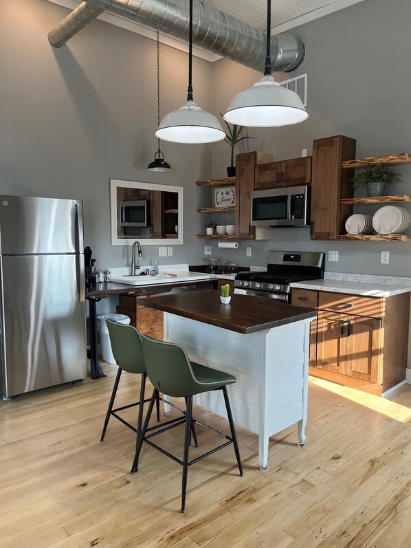 A modern kitchen with stainless steel appliances, wooden cabinets, and a central island with bar stools.