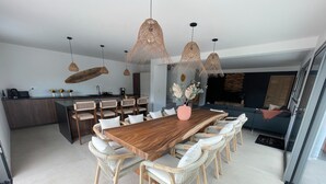 Un comedor moderno con una mesa de madera, sillas de mimbre e iluminación colgante.