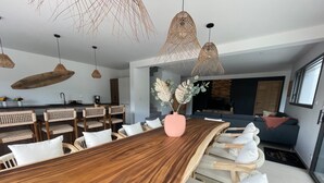 Un comedor moderno con una mesa de madera, sillas de mimbre e iluminación colgante.