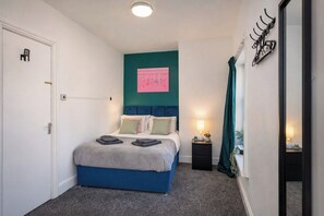 Ein Schlafzimmer mit einem Bett, einem Nachttisch, einer Wandleuchte und einer Tür.