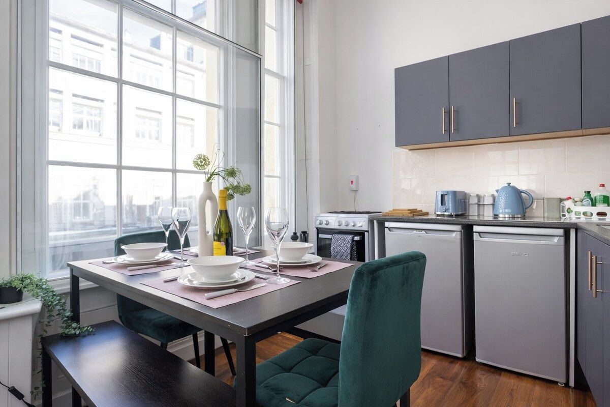 A modern kitchen with grey cabinets, a built-in oven, and a dishwasher.