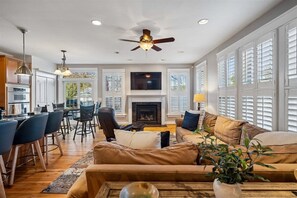 A spacious living area with a fireplace, a ceiling fan, and a dining area with bar stools. - Eastport 4 Bedroom Spacious Gem on Jefferson (Annapolis)