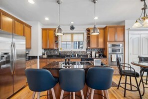 A modern kitchen with wooden cabinets, stainless steel appliances, and a central island with bar stools. - Eastport 4 Bedroom Spacious Gem on Jefferson (Annapolis)