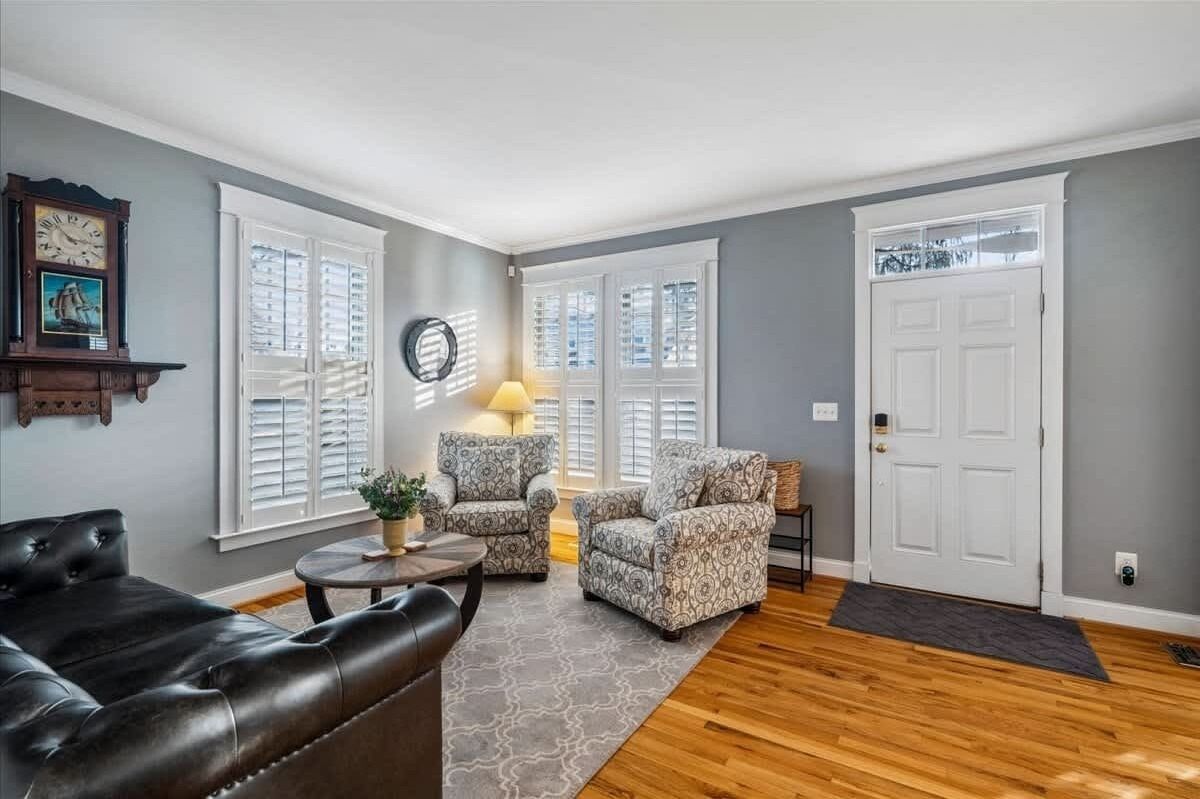 A living room with a leather sofa, patterned armchairs, a round coffee table, and a lamp.