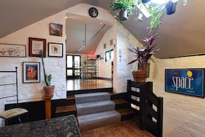 Eine Treppe führt zu einem Essbereich mit Blick auf die Küche, an den Wänden befinden sich gerahmte Kunstwerke und ein Schild mit der Aufschrift 'Space Ibiza Dance'.